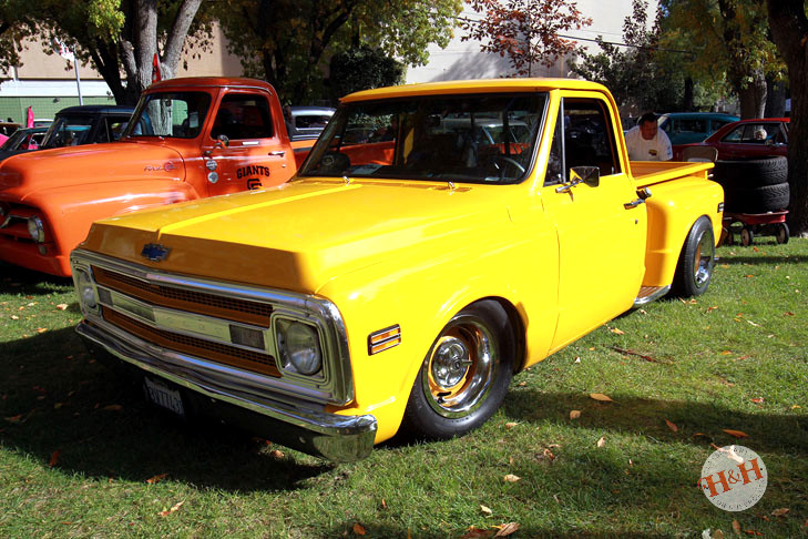 A row of classic GM trucks, featuring an orange and yellow pair of classics